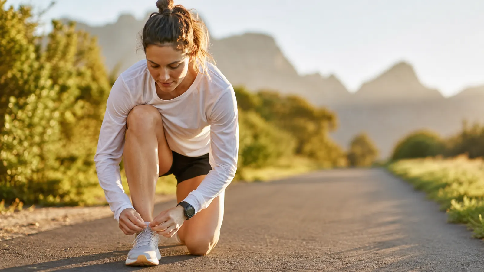 Active adult lacing up running shoes outdoors, looking ready and energetic