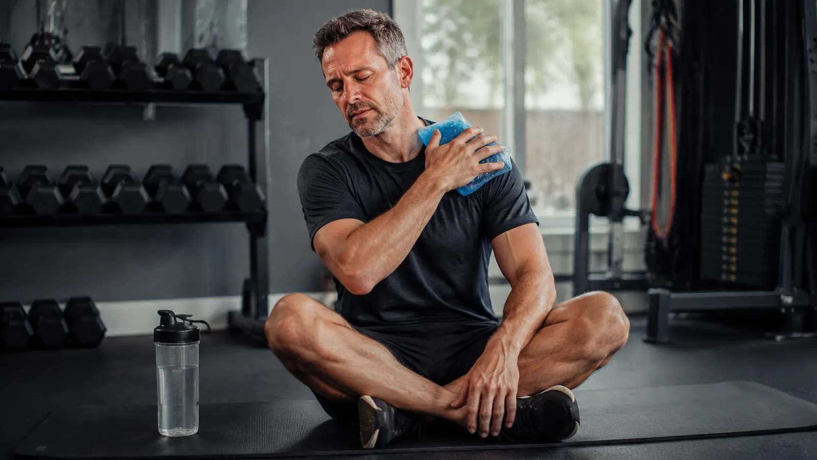 Person sitting on a foam roller mat applying the REVIX ice pack to their shoulder after training